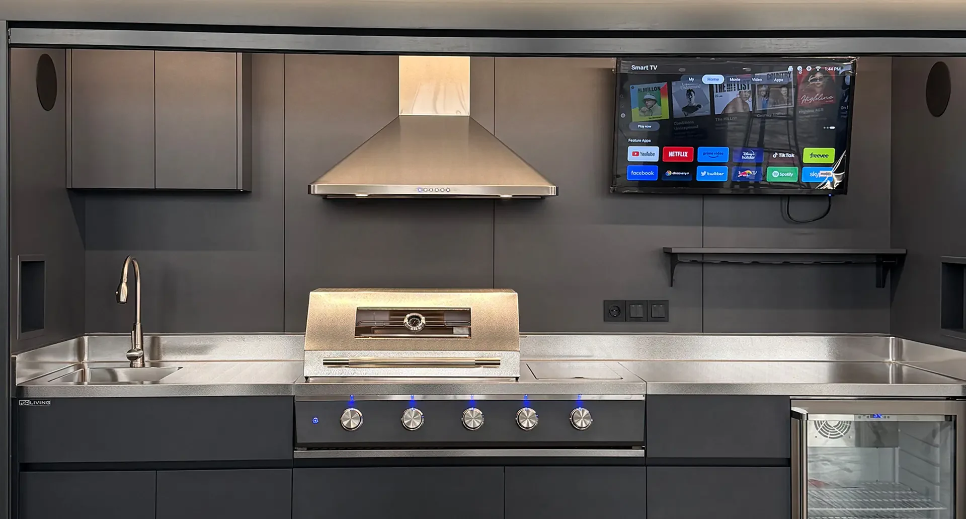 Intérieur Pod Signature BarbecueZone — plan de travail inox, barbecue gaz LED bleu, hotte aspirante, Smart TV et cave à vin intégrée